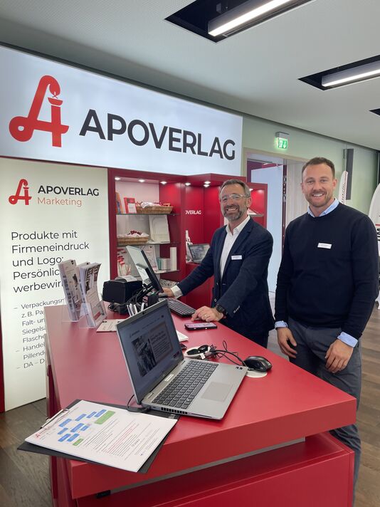 Wolfgang Nagy und Florian Hofmann stehen beim AVS-Stand beim APOkongress in Schladming und lächeln in die Kamera.